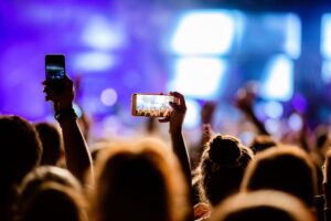 foto di un evento con persone che riprendo con il telefono