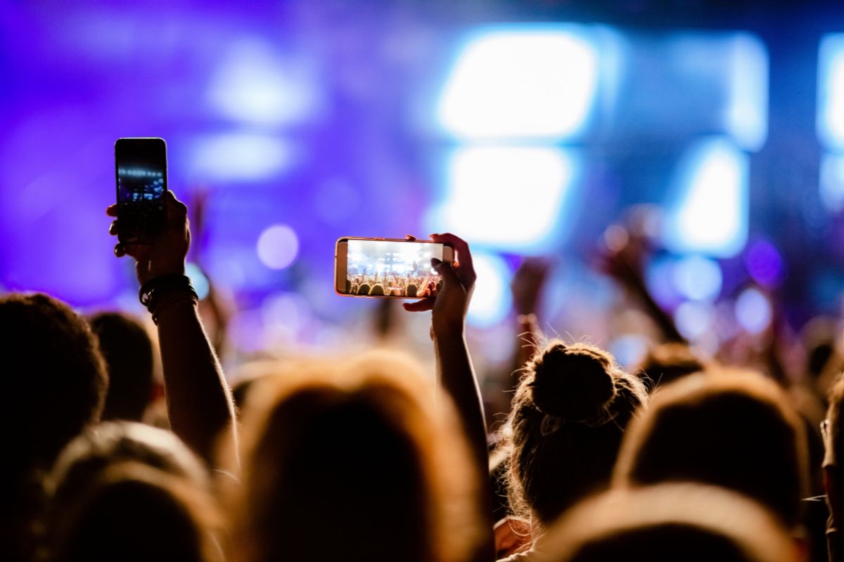 foto di un evento con persone che riprendo con il telefono